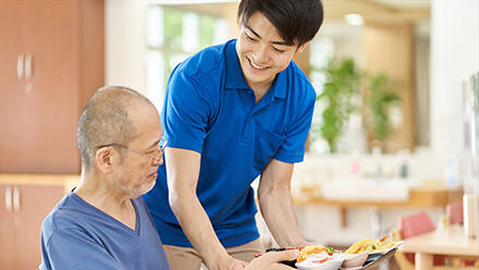 高齢者に食事を運ぶ介護職